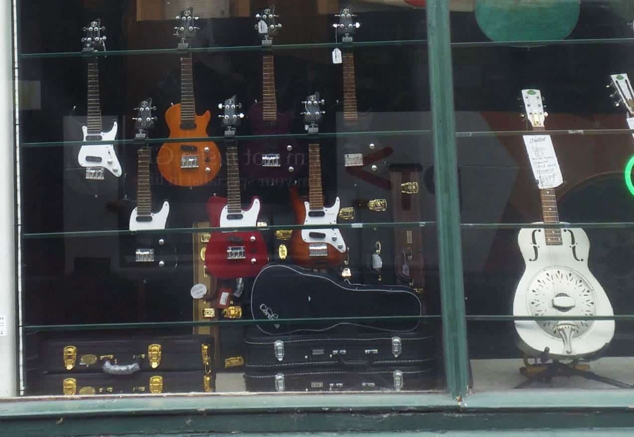 A shop window displaying guitars on a Melbourne street