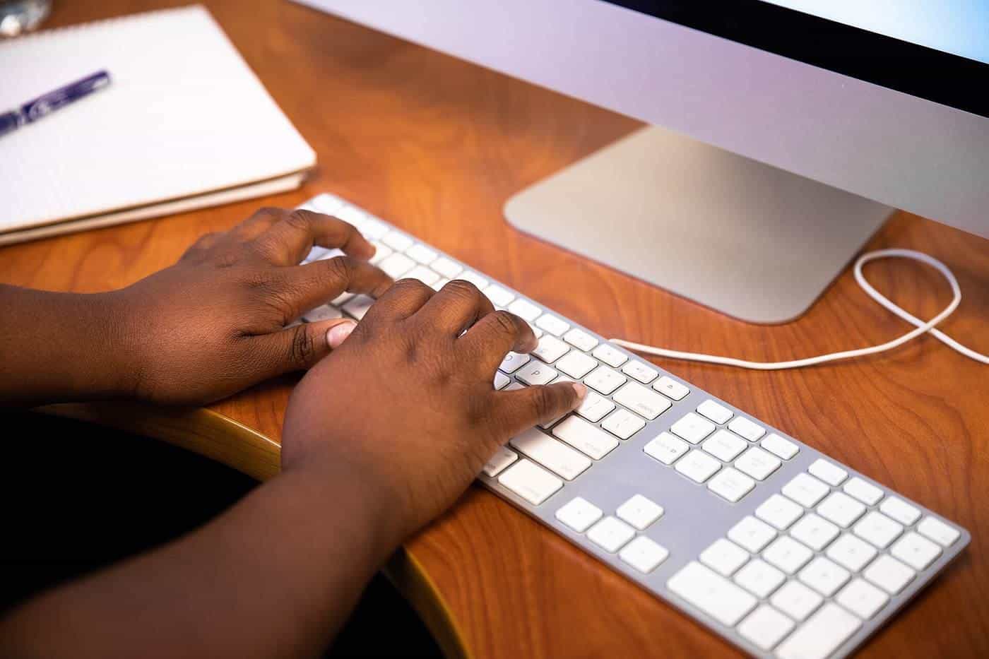 Hands typing on a white desktop keyboard
