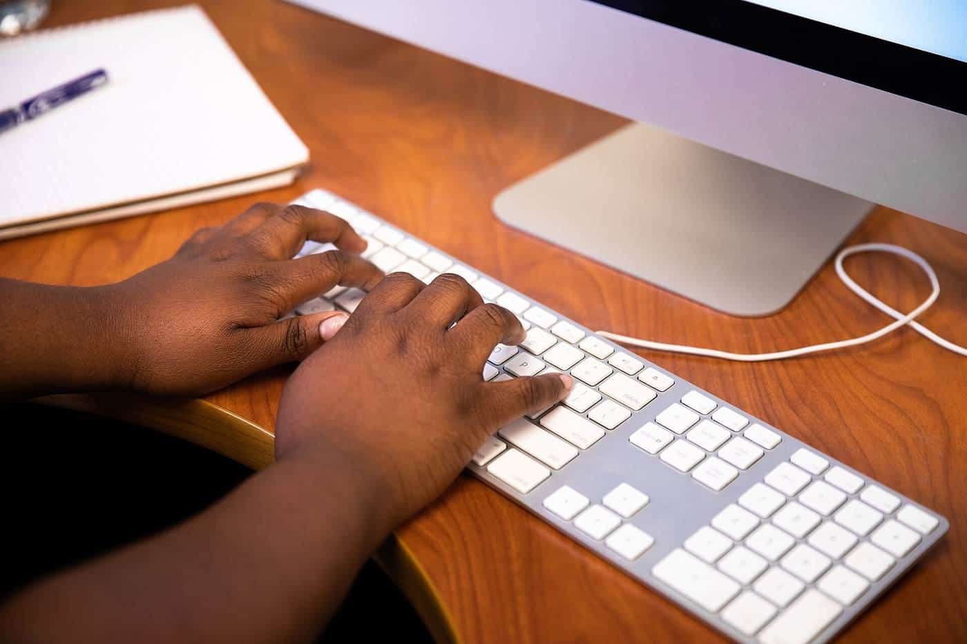Hands typing on a white desktop keyboard